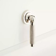 a close up of a metal handle on a white door with an object in the background