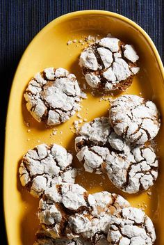 several powdered sugar cookies on a yellow plate