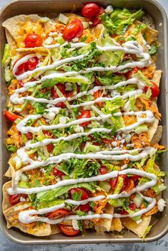 nachos with lettuce, tomatoes and cheese drizzled on top