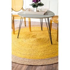 a round rug on the floor in front of a table with two chairs and a vase