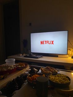 a television sitting on top of a table filled with plates and bowls of food next to a flat screen tv