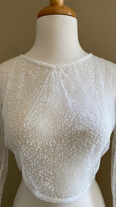 a white dress on a mannequin dummy with sheer sleeves and beadings