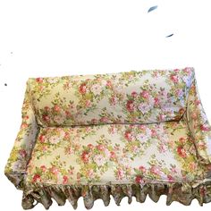 a floral couch with ruffles on the bottom and sides, sitting in front of a white background