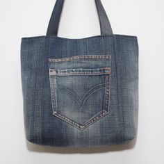 a denim tote bag hanging on the wall with a pocket in front of it