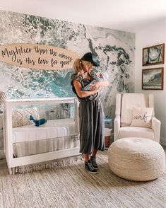 a woman holding a baby in her arms while standing next to a crib