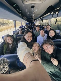 a group of people riding on the back of a bus with their arms around each other