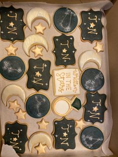 a box filled with decorated cookies in the shape of stars and moon's names