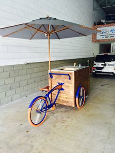 an orange and blue bike is parked in front of a food cart with an umbrella