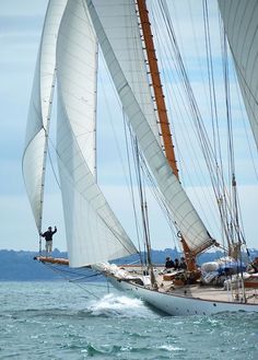 a man standing on top of a sailboat in the ocean