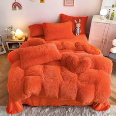 an orange bed with fluffy pillows on it