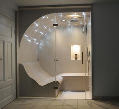 a bathroom with a curved glass shower door and lights on the side of the bathtub