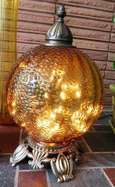 a glass ball light sitting on top of a tile floor next to a brick wall