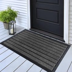 a black door mat sitting on top of a wooden floor next to a potted plant