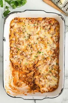 lasagna casserole in a white dish with parsley on the side