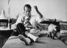 a man sitting on top of a bed next to a teddy bear wearing a tie