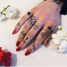 a woman's hand with tattoos on it and flowers around the ring finger area