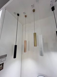 three different lights hanging from the ceiling in a room with white walls and flooring