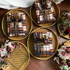 four wicker trays with wrapped gifts tied in twine and flowers on them