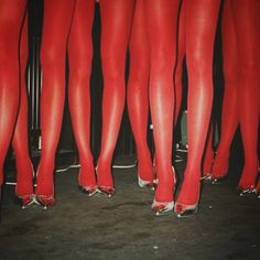 there are many pairs of red high heeled shoes on the feet of women in tight stockings