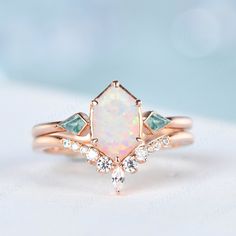 a white opal and black diamond ring on top of a white surface with light blue background