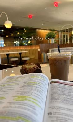 an open book sitting on top of a table next to a cup of coffee