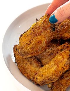 a woman's finger pointing at fried food in a white bowl