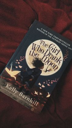 the girl who drank the moon by kelly ranhill is on a red bed sheet