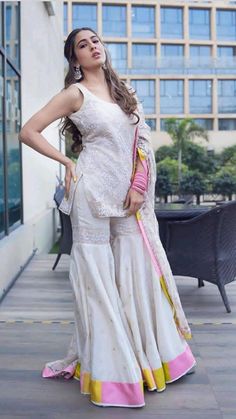 a woman in white and pink outfit posing for the camera