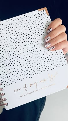 a woman holding a notebook with polka dots on it