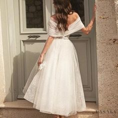 a woman in a white dress is walking out of a door with her hand on her hip