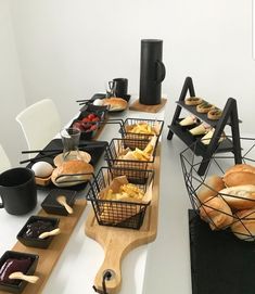 an assortment of breads and pastries on wooden serving trays in front of a white wall