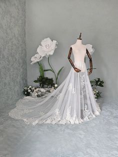 a wedding dress on display with flowers in the background