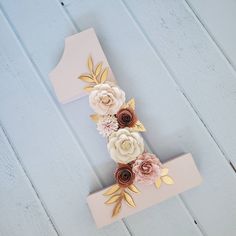 a wooden letter decorated with flowers and leaves