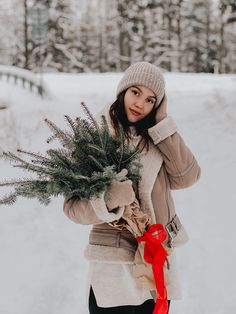 a woman holding a christmas tree in the snow