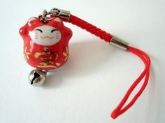 a red glass bead with a white cat on it's side and a red cord