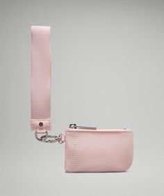 a pink purse with a metal keychain hanging from it's side on a gray background