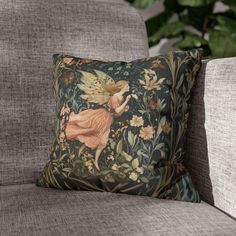 a pillow with an image of a fairy on it sitting on a couch next to a plant