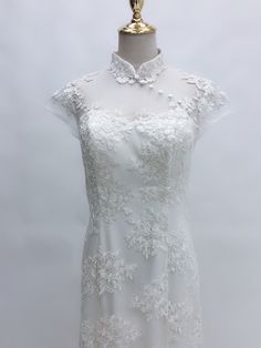 a white dress on a mannequin with an open neckline and lace detailing