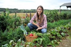 a woman kneeling down in the middle of a garden with lots of plants and vegetables