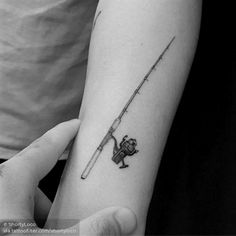 a person with a tattoo on their arm holding a fishing rod