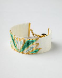 Add a touch of elegance to your look with this handcrafted Miyuki bead bracelet, carefully designed using the loom technique. The bracelet showcases a striking swan-inspired geometric pattern, blending crisp white beads with luxurious gold and vibrant green accents. Expertly made with premium Miyuki glass beads, known for their precision and durability, this piece is finished with a gold-plated clasp and chain for an adjustable fit, making it both comfortable and stylish. The detailed beadwork o White Handwoven Bracelets With Round Beads, White Woven Bracelet Jewelry, White Woven Jewelry Bracelet, White Handwoven Bracelets, White Elegant Woven Jewelry, Elegant White Woven Jewelry, Swan Bracelet, Miyuki Bead, Green Shades