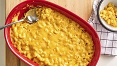 a red bowl filled with macaroni and cheese on top of a wooden table