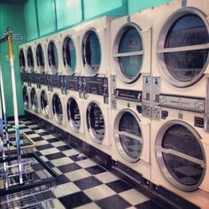 a row of washers and dryers in a room with black and white checkered floor