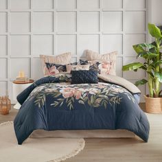 a bed with blue comforter and pillows in a room next to a potted plant