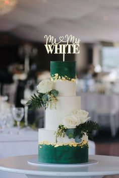 a white and green wedding cake sitting on top of a table