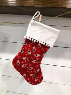 a red christmas stocking hanging from a line on a wooden floor with white trim