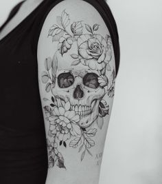 a woman's arm with a skull and flowers on it