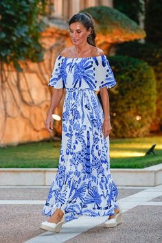 a woman in a blue and white dress walking down the street