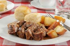 a white plate topped with meat and potatoes