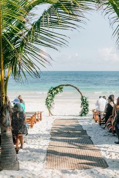 a beach wedding on the sand under a palm tree